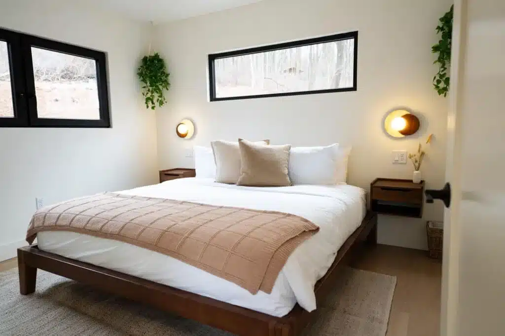 Modern cabin bedroom with wooden bed, white linens, and natural light at Royal Oak Retreat in Shenandoah Valley VA