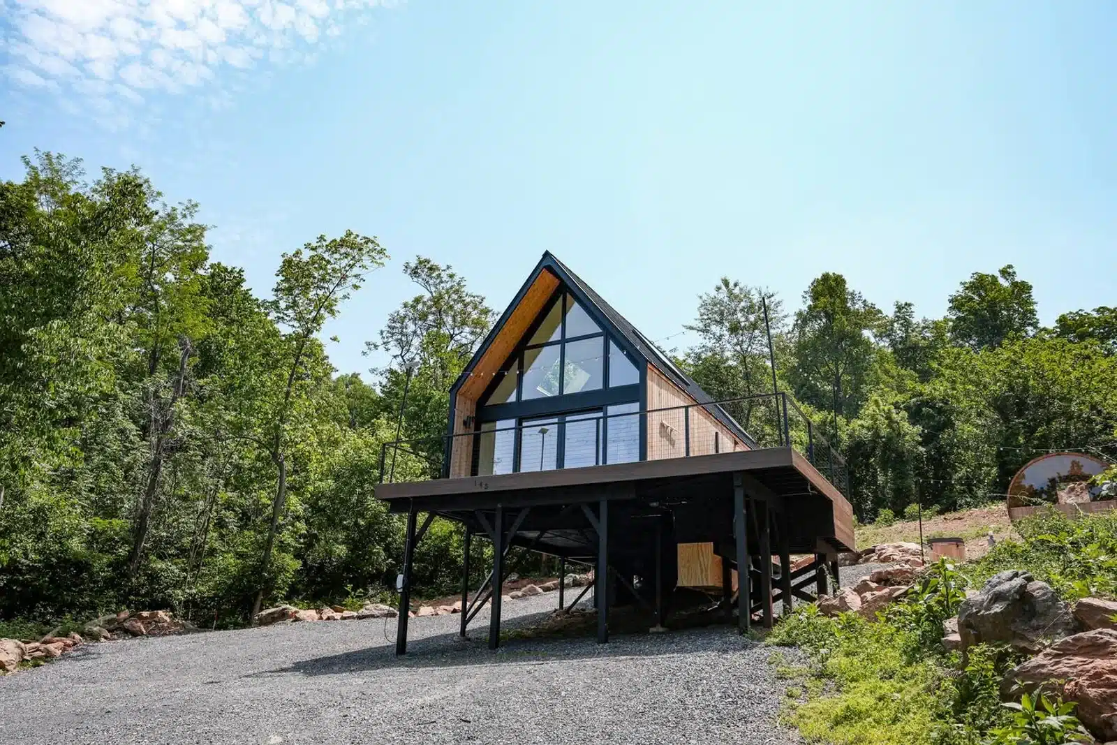 Modern A-frame cabin with large windows and wood details nestled in forest at Royal Oak Retreat