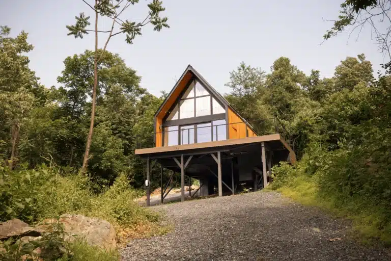 Modern A-frame cottage with wood tones and large windows nestled in forest at Royal Oak Retreat