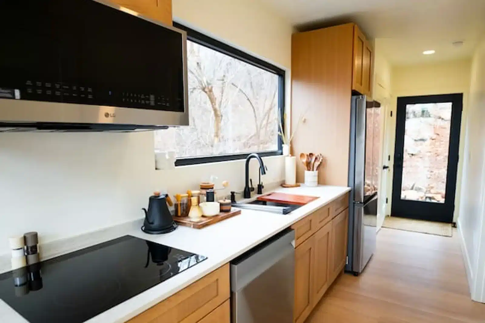 Modern wellness cabin kitchen with warm wood cabinets, white countertops, stainless steel appliances in Shenandoah Valley