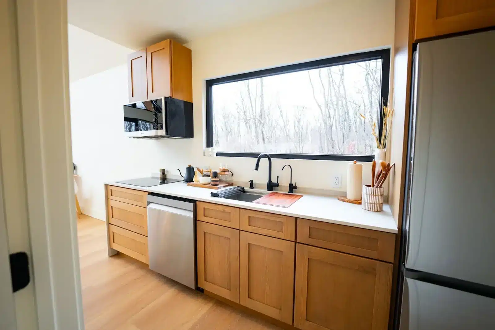 Modern honeymoon cabin kitchen with wood cabinetry, stainless steel appliances, and forest views in Virginia