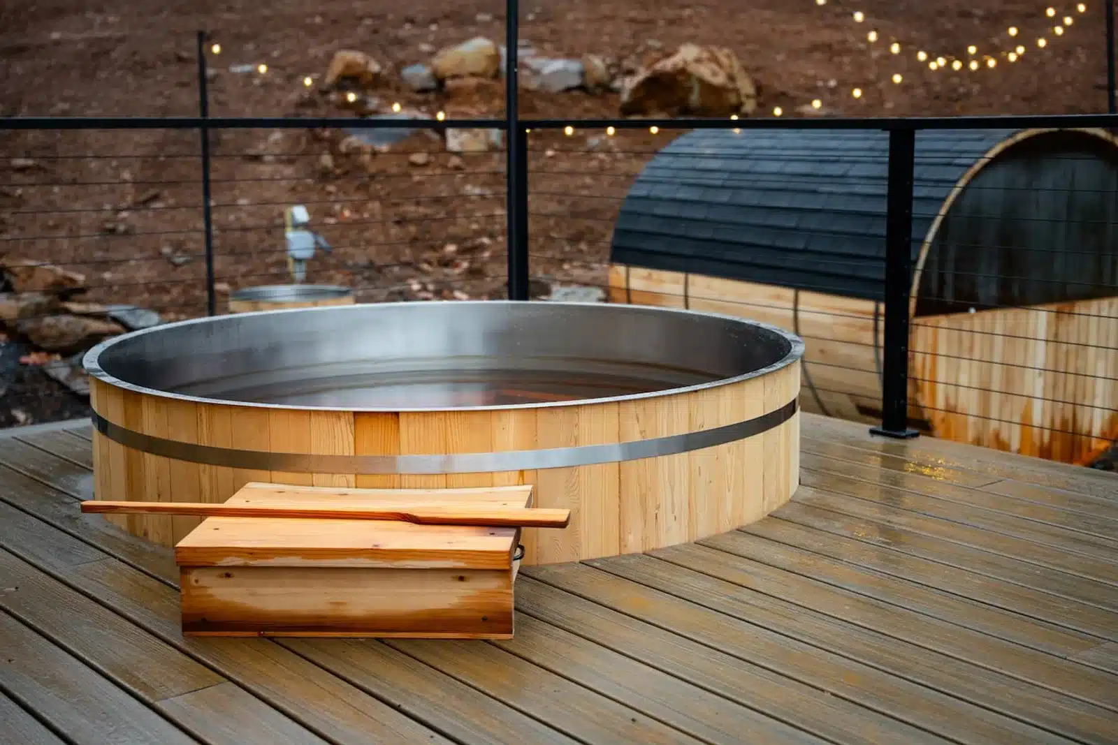 Barrel sauna and wooden hot tub with string lights on stone patio at Royal Oak Retreat in Shenandoah Valley