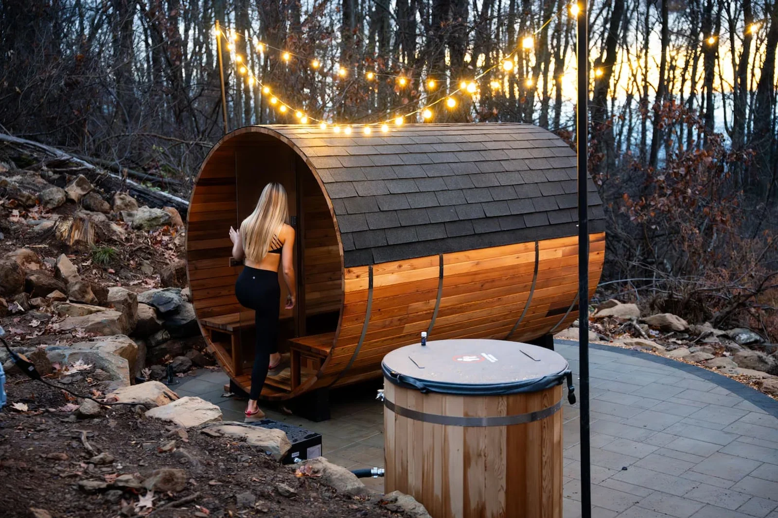 Barrel sauna with string lights and ice bath on forest patio at Royal Oak Retreat cabin